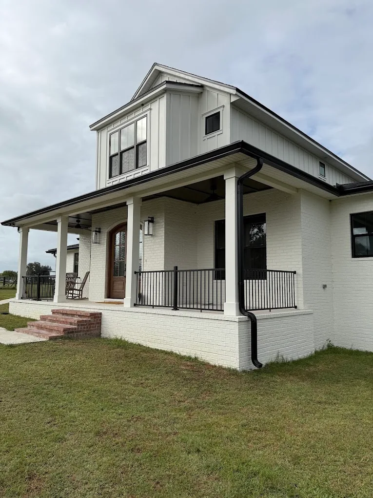 White home with black gutters and a downspout along the front porch.
